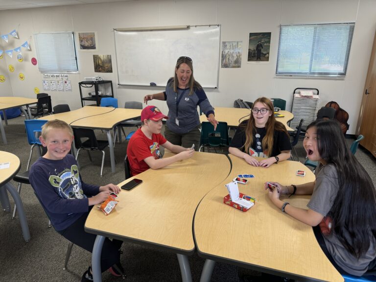 A teacher and student splay uno at a table