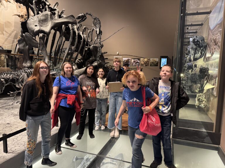 Students stand in front of a TREX Fossils at a museum