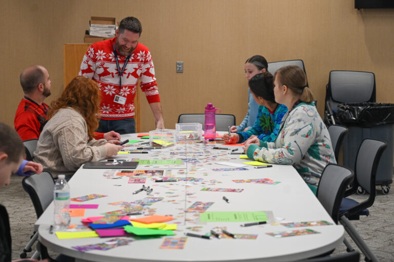 Kelsey Peak Teachers, Students, and Counselors stand around a table making cards, and laughing