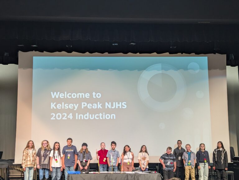 Students Stand in front of an NJHS Induction Sign