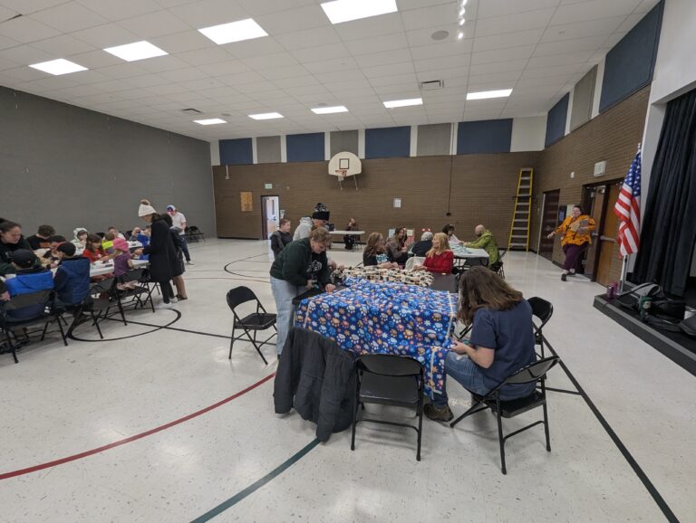 A large group of Volunteers tie quilts for the road home